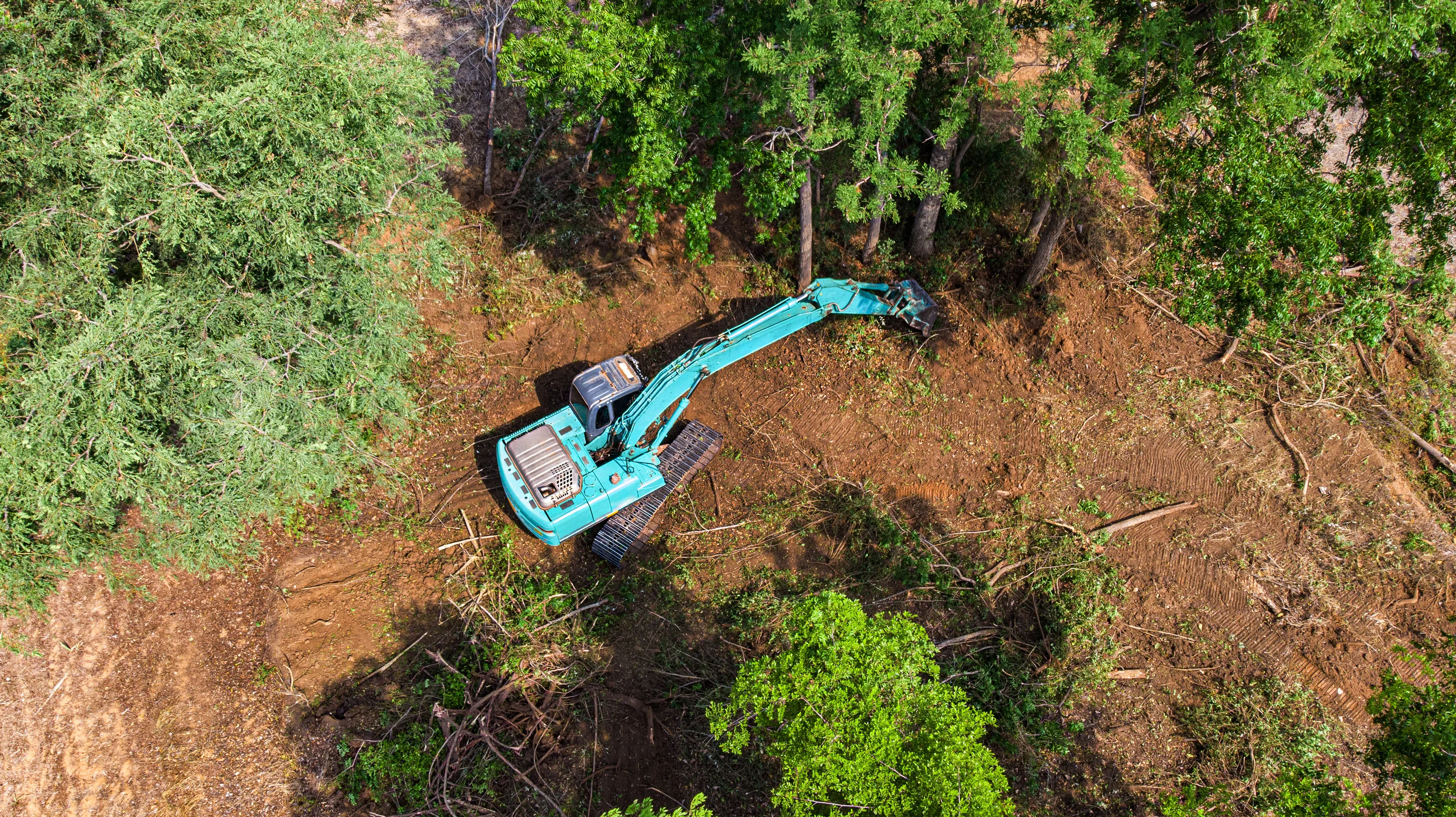 Aerial drone view of an excavator clearing forest land for a Rangeland Solutions project